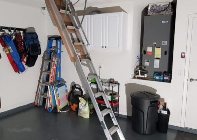 Professional attic ladder installation completed showing aluminum pull-down ladder fully extended to garage floor in South Jacksonville Florida home